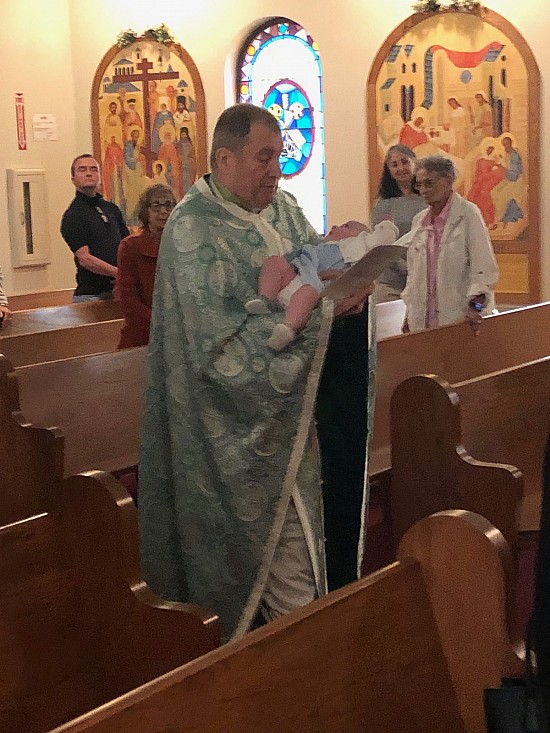 Fr. Sergei carries Lizzie from the rear of the church towards the Altar